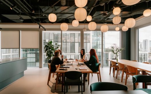 Groupe de personnes assises autour d’une table lors d’une réunion professionnelle dans un bureau moderne.